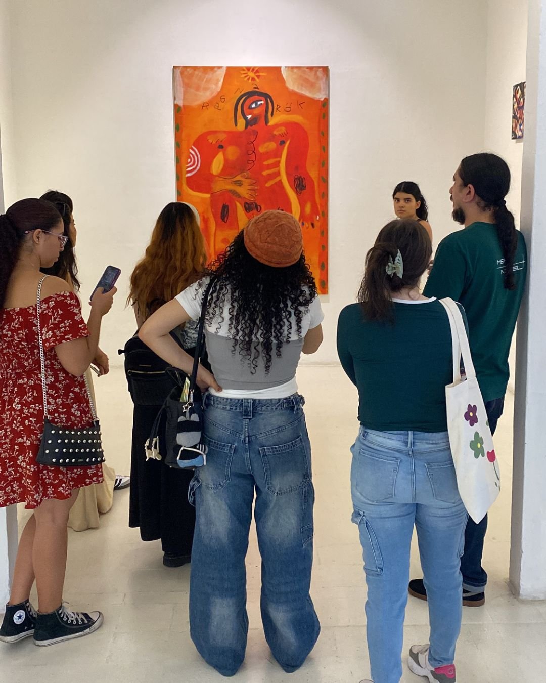 Grupo observando una pintura naranja de gran formato en una galería, una salida de la comunidad de nuestros talleres de arte