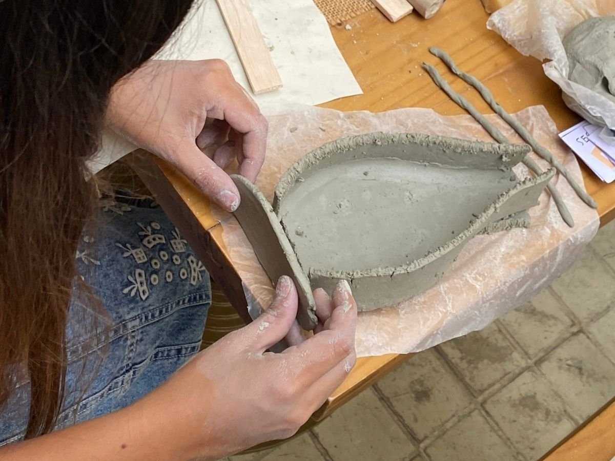 Manos modelando arcilla con rodillo y esponjas en una de las sesiones de modelado de nuestros talleres de arte